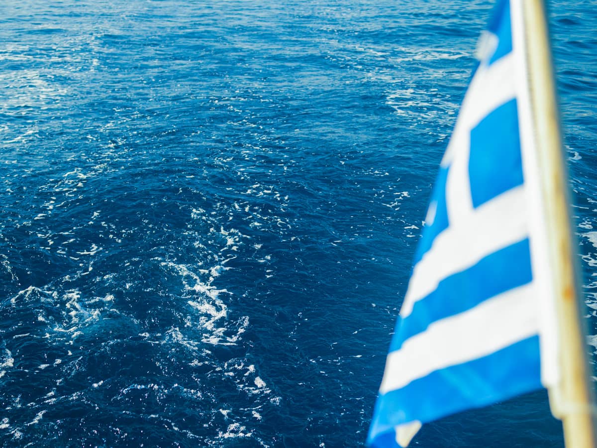 Greek flag over the wake on the sail home